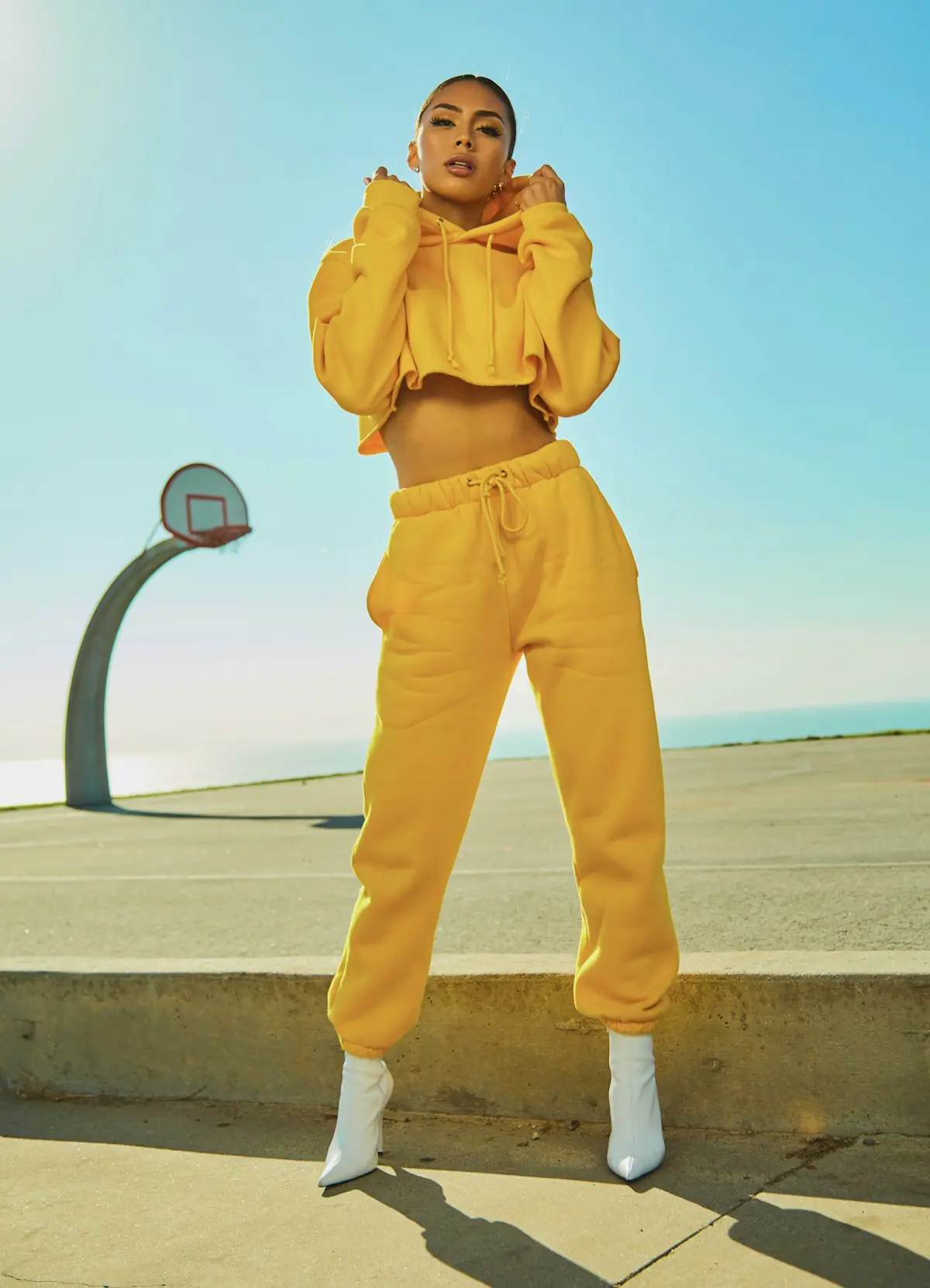 Model wearing a yellow tracksuit outdoors in strong sunlight
