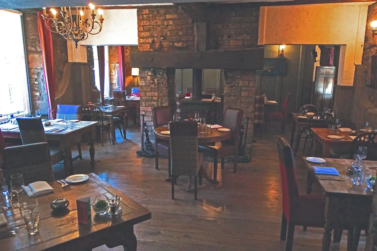 Warm restaurant dining room with wooden tables and shaded lamps